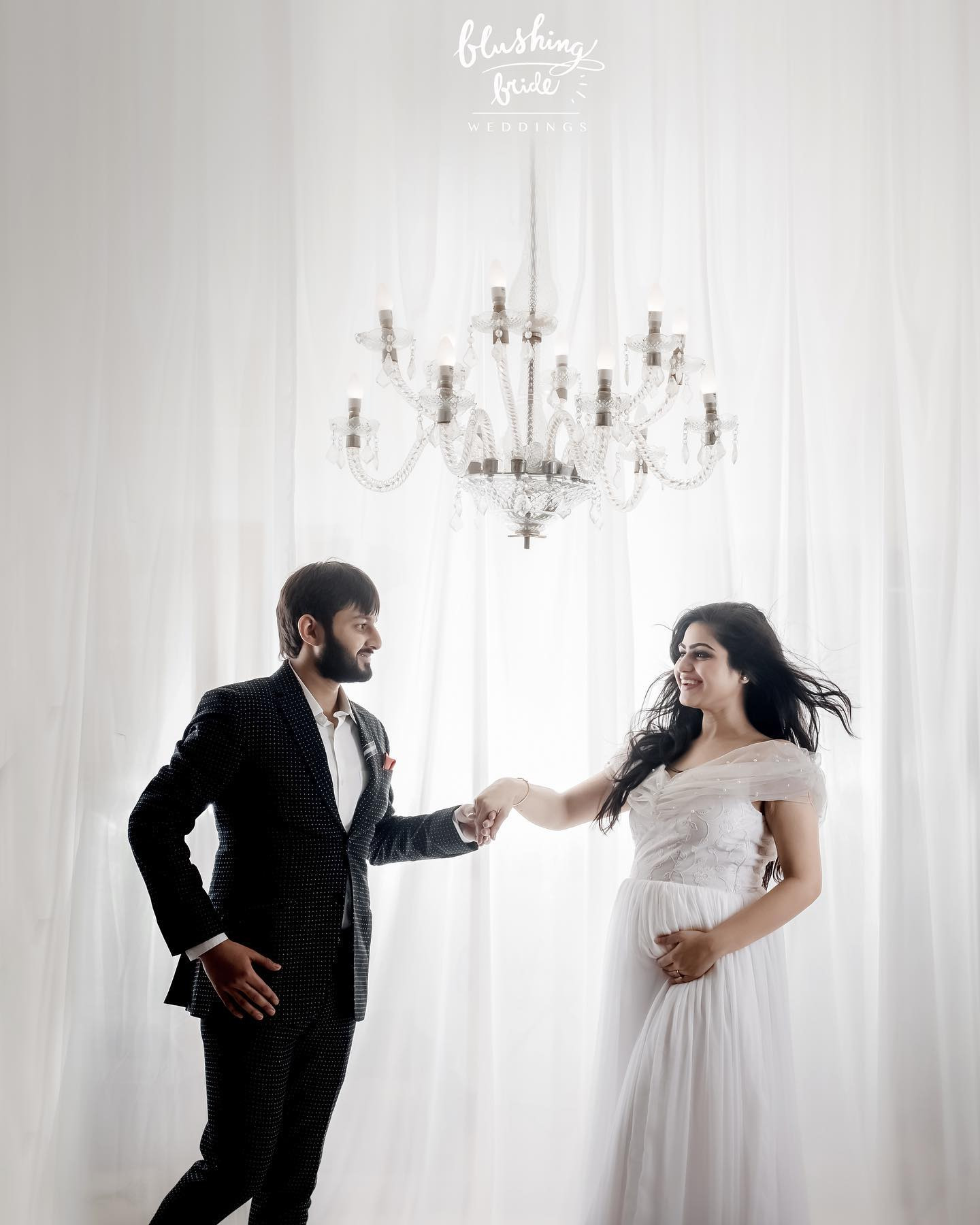 Maternity photography by Blushing Bride, an expectant couple photographed against white drapes
